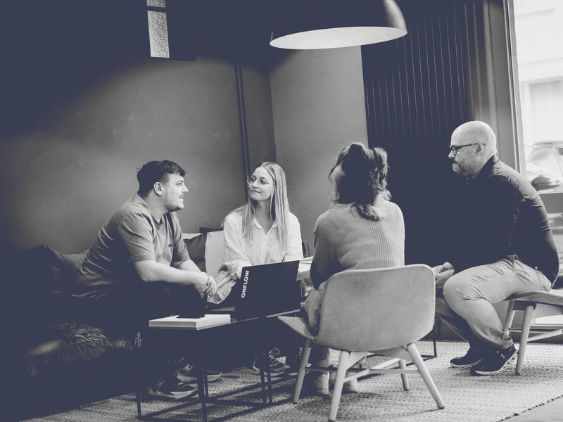 Vier Personen der Agentur besprechen sich um einen Couchtisch