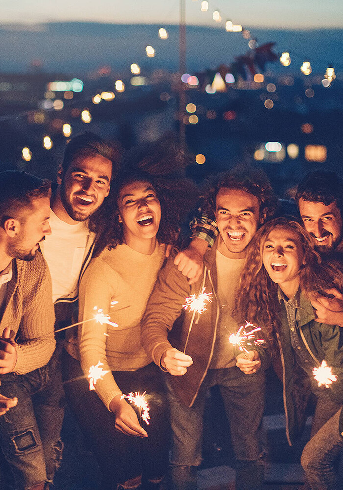 Freunde mit Wunderkerzen auf einer Dachterrasse über der Stadt
