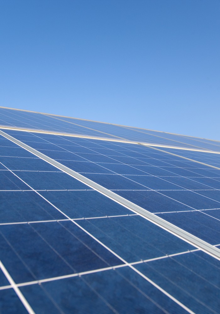 Blaue Photovoltaik-Module in Reihen unter wolkenlosem Himmel